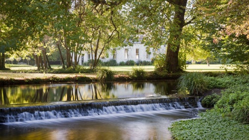 An image of the River Wandle cascade with Morden Hall house in the background